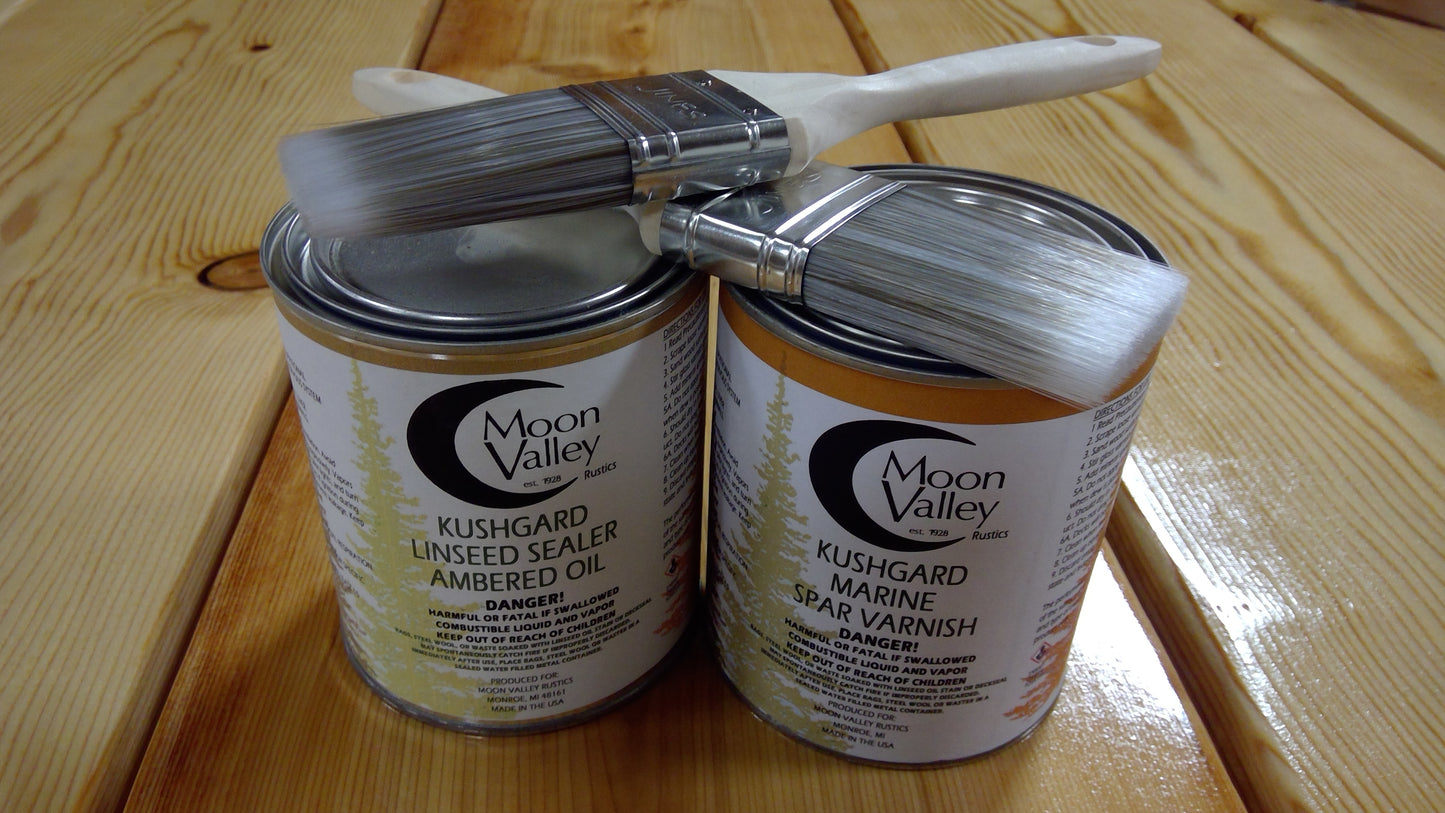 Two cans of Moon Valley Kushgard Linseed Sealer and Varnish on a wooden surface with a brush.