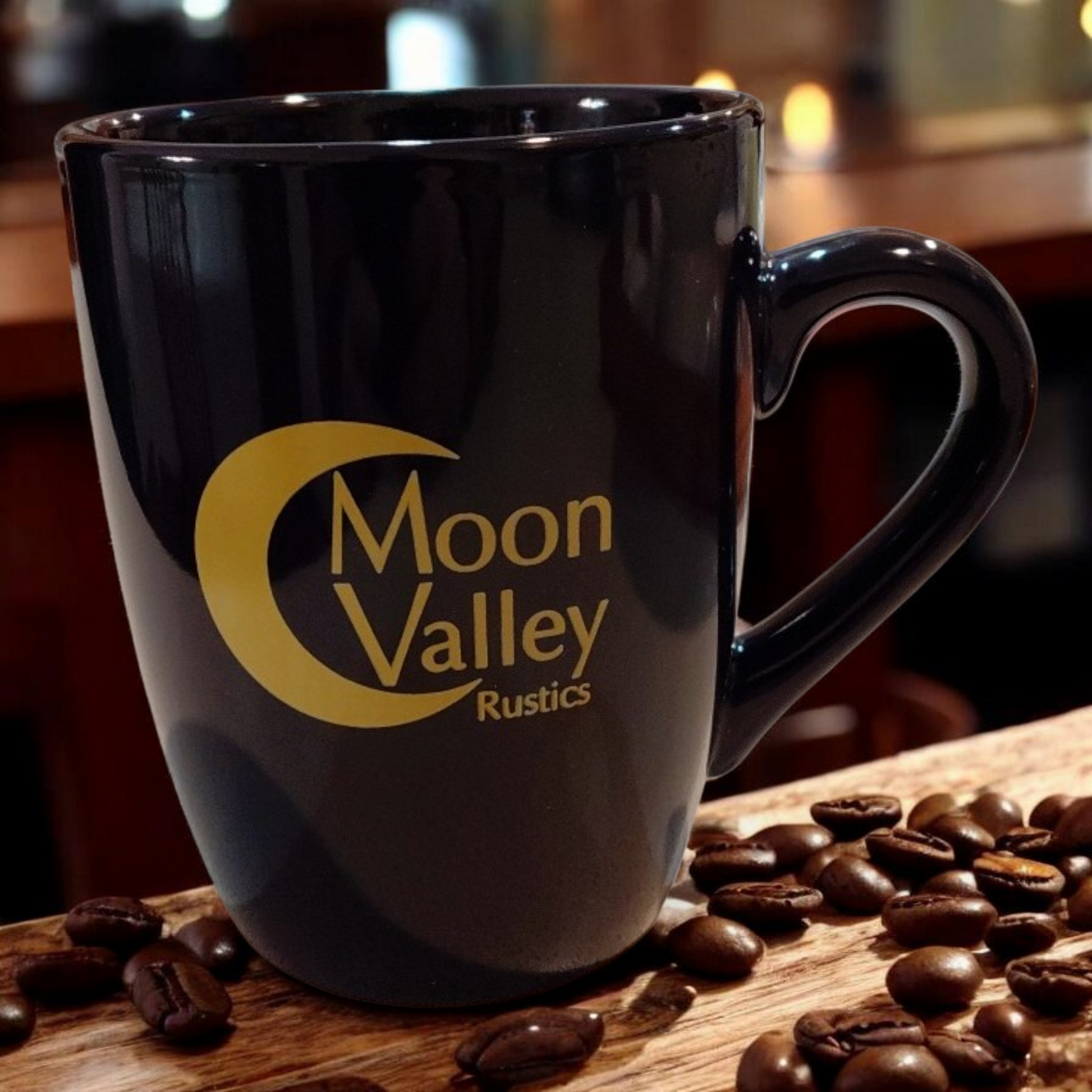 Black mug with 'Moon Valley Rustics' logo on a wooden surface with coffee beans